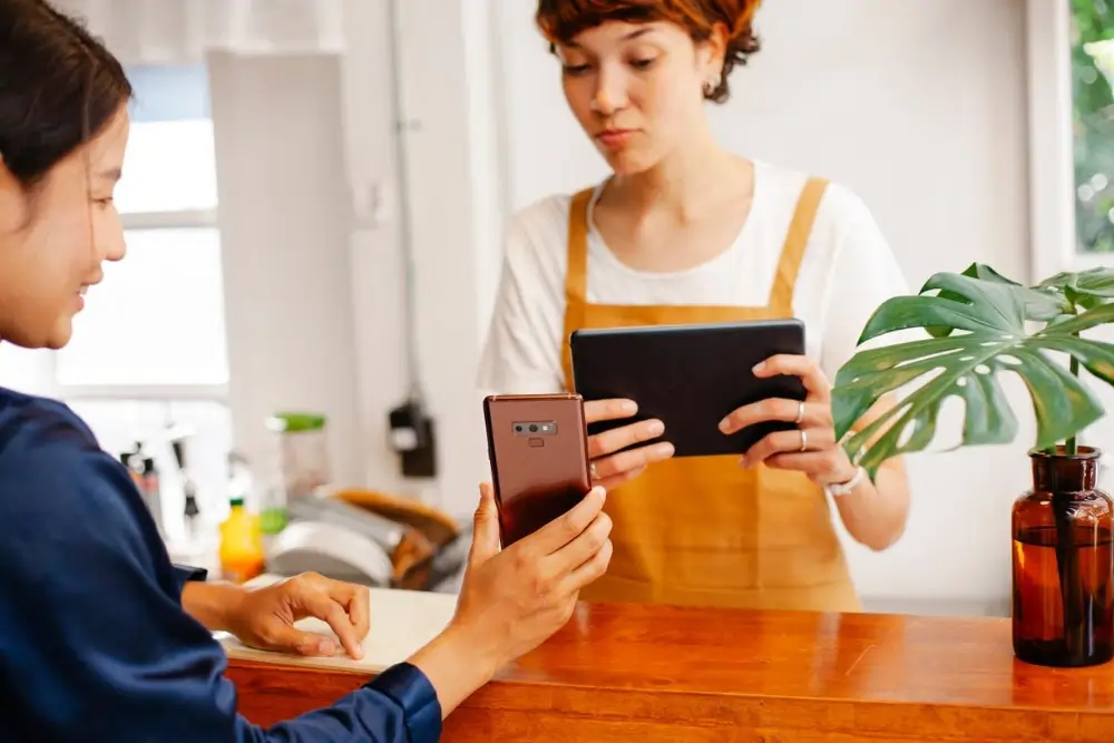 Business owner asking a satisfied customer for an online review on a digital device
