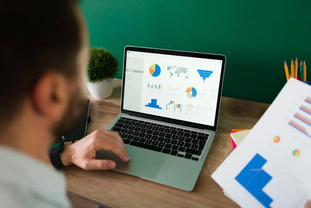 Founder reviewing startup marketing strategy on laptop with growth charts and brand awareness icons
