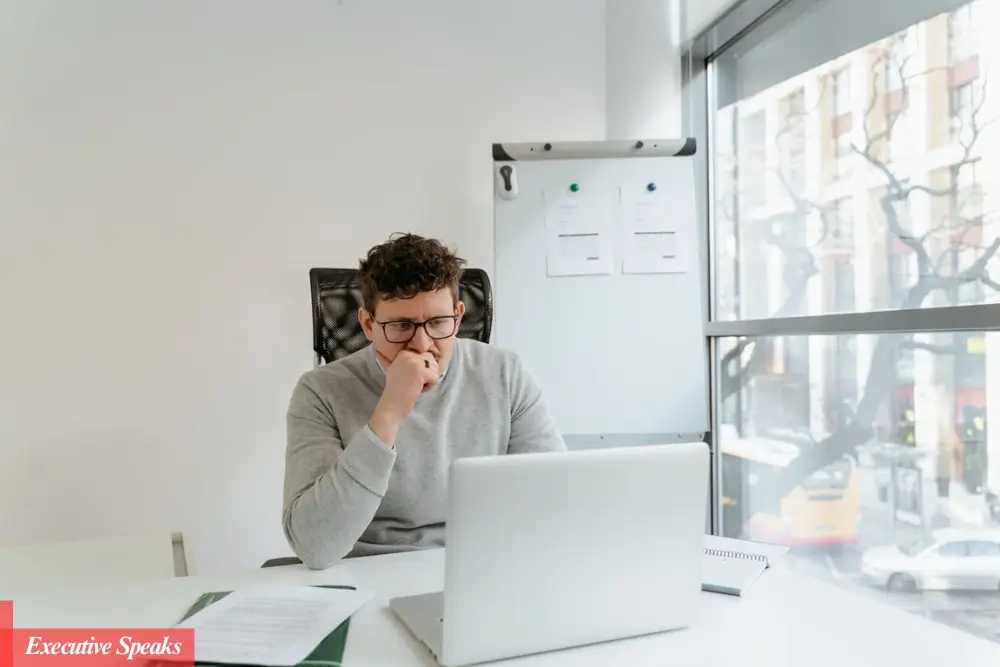 An employee sitting at a desk looking disconnected while reviewing work